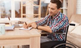A young man in a wheelchair working from home.