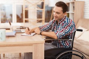 A young man in a wheelchair working from home.